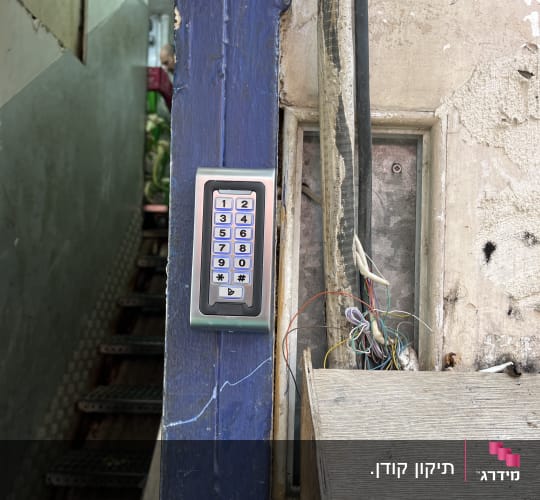 מערכת אינטרקום מותקנת על קיר עם חוטים חשופים.